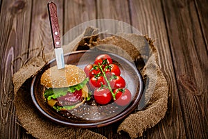 From above view of rustic serving appetite beef burger with knife on wooden table. gastro pub