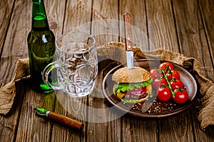 From above view of rustic serving classic beef burger with glass of beer on wooden table. gastro pub