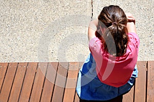 Above view  of sad young girl covering her face and crying in school yard