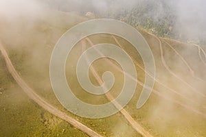 Above view of serpentine road partly hidden by cloud