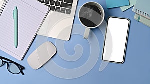 Smart phone, coffee cup and notepad on blue background.