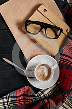 Above view of Smart phone with notebook and cup of latte coffee on black wooden background.