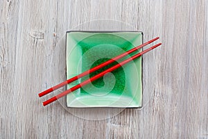 Above view square saucer with chopsticks on gray