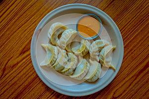 Above view of steamed Momo served in a white plate. A popular Nepalese food that is also common in Chiana, Bhutan, Tibet