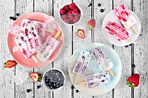 Above view table scene of homemade berry yogurt ice pops over rustic white wood