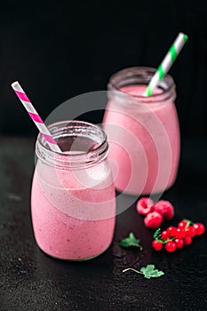 From above view of two jars with yogurt smoothie with cranberry, raspberry on black background.