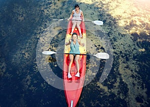 Above view of two smiling friends kayaking on the ocean together over summer break. Portrait of happy women canoeing and