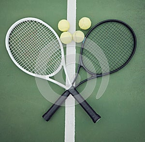 Above view of two tennis rackets and balls on an empty court in a sports club. Aerial view of black and white tennis