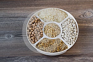 Uncooked dried chickpeas, wheat, rice and white beans in divided plate.Ashure Day