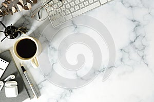 Above view woman workspace with notebook, glasses, coffee cup and wireless ear phones on marble table