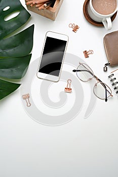 Above view of workplace with mock up smart phone, coffee cup, glasses, wallet and copy space on white background.