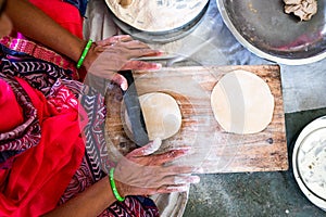 Above view of young indian woman making fresh homemade rotis and chapati, a classic indian street food