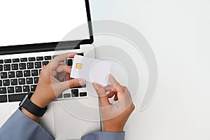 Above view of young woman holding credit card making purchase, payments on web stores via laptop