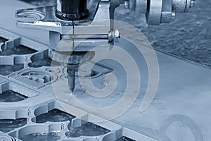 The abrasive waterjet cutting machine cutting the metal plate in the light blue scene photo