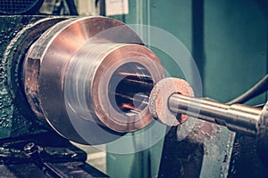 Abrasive wheel on the mandrel on the machine in front of the cylindrical part is ready for metal processing by grinding