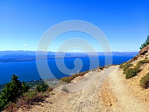 Abrupt dirt road in extreme landscape with Patagonian lake and blue sky. extreme nature