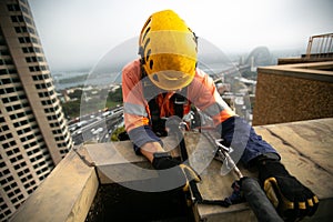 Abseiler inspector wearing yellow head fall protection safety helmet fall body harness, climbing over the edge photo
