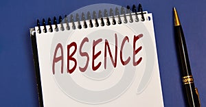 ABSENCE - word in a white notebook on a blue background with a pen