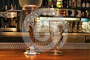 Absinth fountain and glass with spoon on bar counter close-up. photo