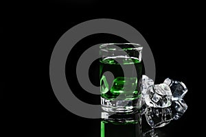 Absinthe shot with ice cube on black background