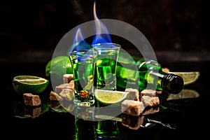 Absinthe shots with sugar cubes. absinthe poured into a glass. bottle of absinthe with brown sugar and lime isolated on black