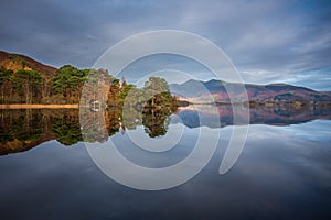 Absolutely stunning vibrant Autumn sunrise landscape image looking from Manesty Park in Lake Distict towards sunlit Skiddaw Range