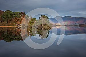 Absolutely stunning vibrant Autumn sunrise landscape image looking from Manesty Park in Lake Distict towards sunlit Skiddaw Range