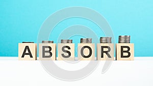 absorb text on wooden blocks with coins on blue background