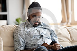 Absorbed african guy read internet news using smartphone at home