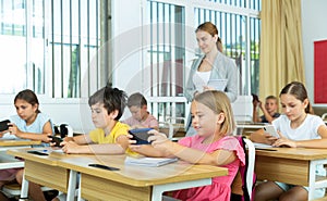 Absorbed preteen school children using mobile phones at lesson