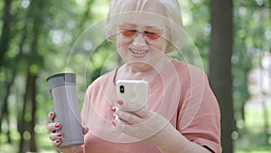 Absorbed senior woman looking at smartphone screen and laughing. Portrait of relaxed Caucasian retiree watching comedy
