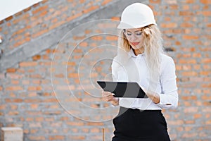 Absorbed in the work of a woman engineer working with a tablet on the background of the construction site. Portrait of a