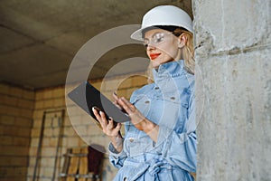 Absorbed in the work of a woman engineer working with a tablet on the background of the construction site. Portrait of a