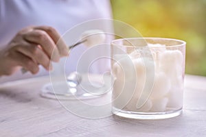 Absorbent cotton balls and cutton sawbs in cotton container with morning sunrise.