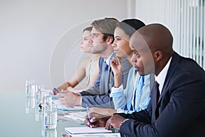 Absorbing all the information. businesspeople taking notes while listening to a presentation at a conference.