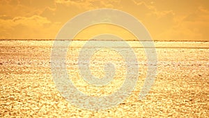 Abstract aerial sea summer ocean sunset nature background. Small waves on calm water surface in motion blur with golden