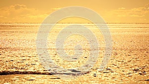 Abstract aerial sea summer ocean sunset nature background. Small waves on calm water surface in motion blur with golden