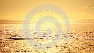 Abstract aerial sea summer ocean sunset nature background. Small waves on calm water surface in motion blur with golden