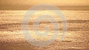 Abstract aerial sea summer ocean sunset nature background. Small waves on calm water surface in motion blur with golden