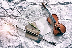 The abstract art design background of violin put beside the opened book and bow