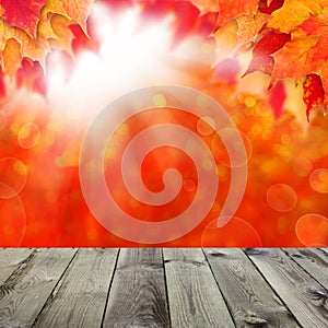 Abstract autumn background with fall maple leaves and sun light with empty dark wooden board background