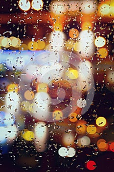 abstract background autumn rain in the night city, drops fall on the window on an October night