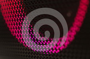 Abstract background of a black patterned lattice behind which glow red LEDs