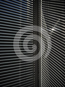 Blinds on the window and a pattern of shadow and light on the wall.