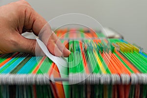 Abstract background colorful hanging file folders in drawer. Mans hand