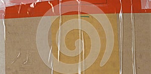 Abstract background. Fragment of brown cardboard transport packaging plastered with colored duct tape and polyethylene.