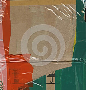 Abstract background. Fragment of brown cardboard transport packaging plastered with colored duct tape and polyethylene.