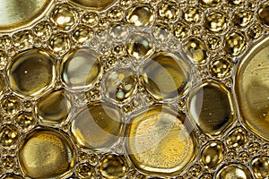 Abstract background of gold colored oil drops on water