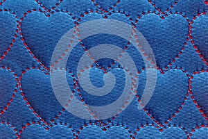 Abstract background heart on textiles, red threads stitched stitches in the shape of hearts on blue cotton, denim