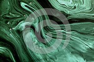 Abstract background made of black and green marble. Acrylic paint flows freely and creates an interesting pattern.